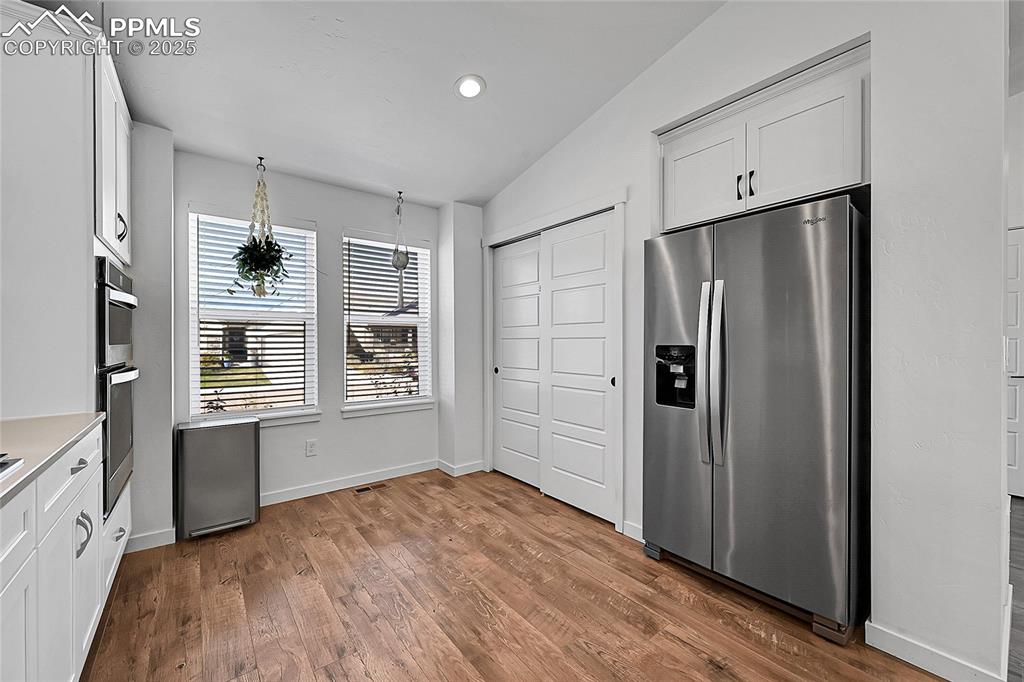 Image 6 of 29: Kitchen with appliances with stainless steel finishes, white cabinets, vaul