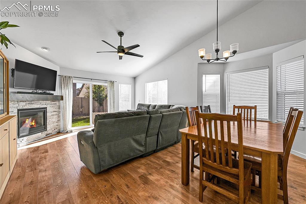 Image 8 of 29: Living room with wood finished floors, a ceiling fan, a fireplace, a chande