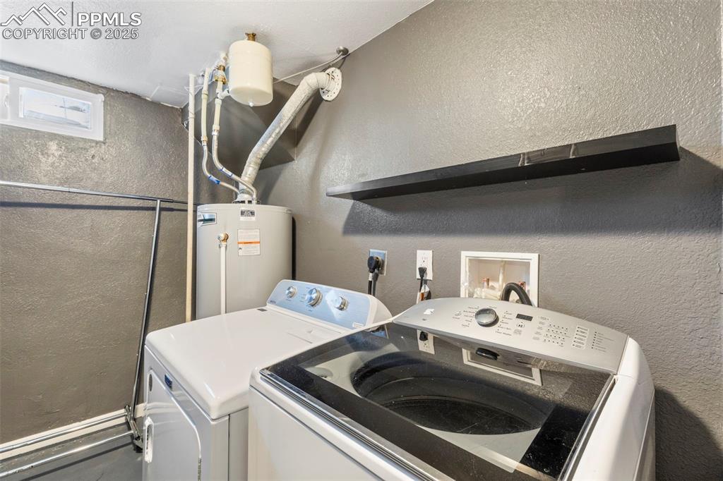 Image 15 of 25: Laundry area featuring a textured wall, separate washer and dryer, and wate