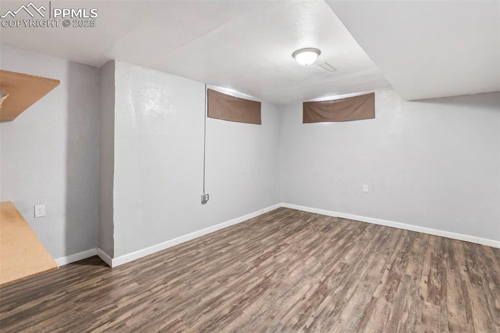 Image 16 of 25: Finished below grade area featuring dark wood/laminate-style floors and bas