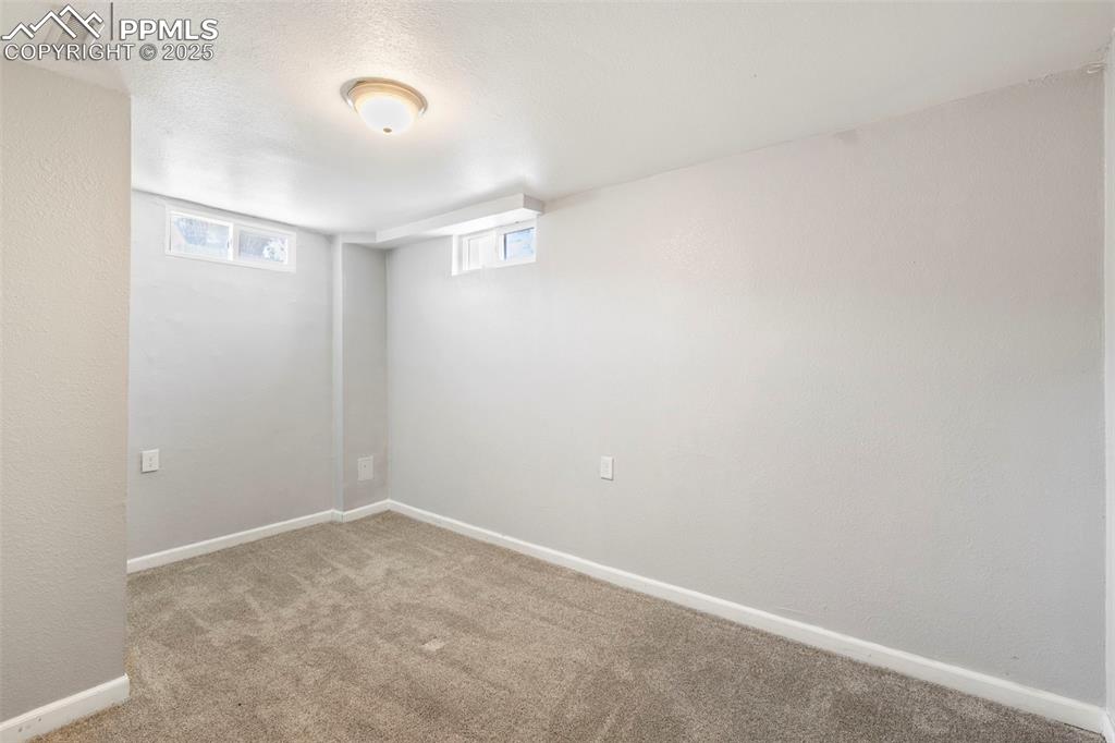 Image 18 of 25: Basement featuring light carpet, a textured ceiling, and a textured wall