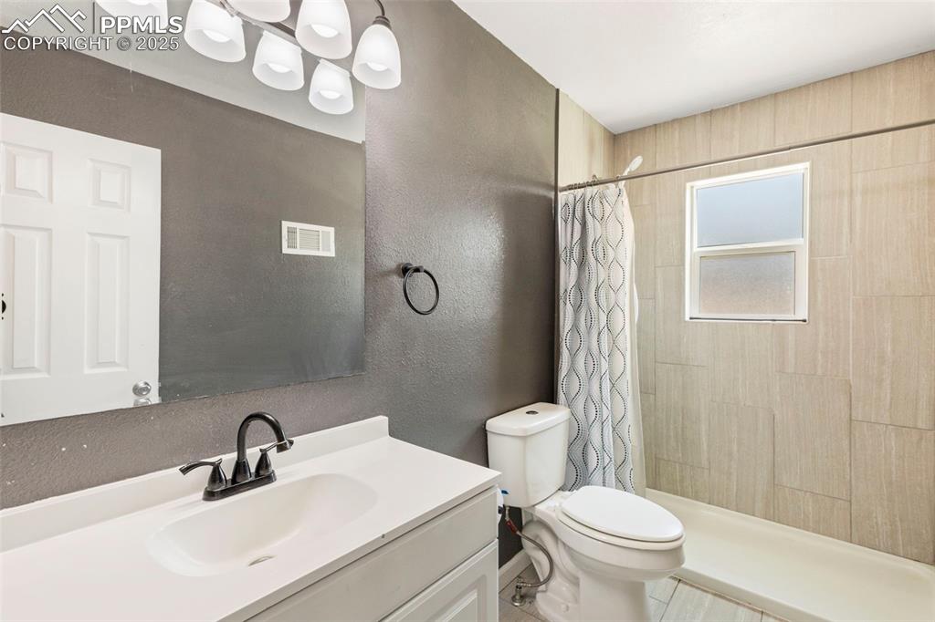 Image 8 of 25: 3/4 bath featuring a textured wall, vanity, and a stall shower