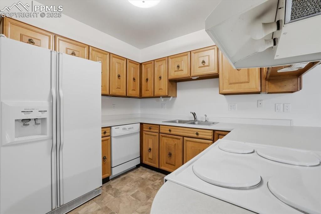 Image 10 of 50: Kitchen featuring white appliances, light countertops, exhaust hood, stone 