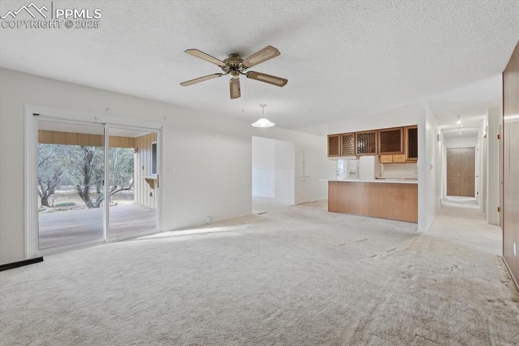 Image 31 of 50: Unfurnished living room featuring a ceiling fan, a textured ceiling, and li