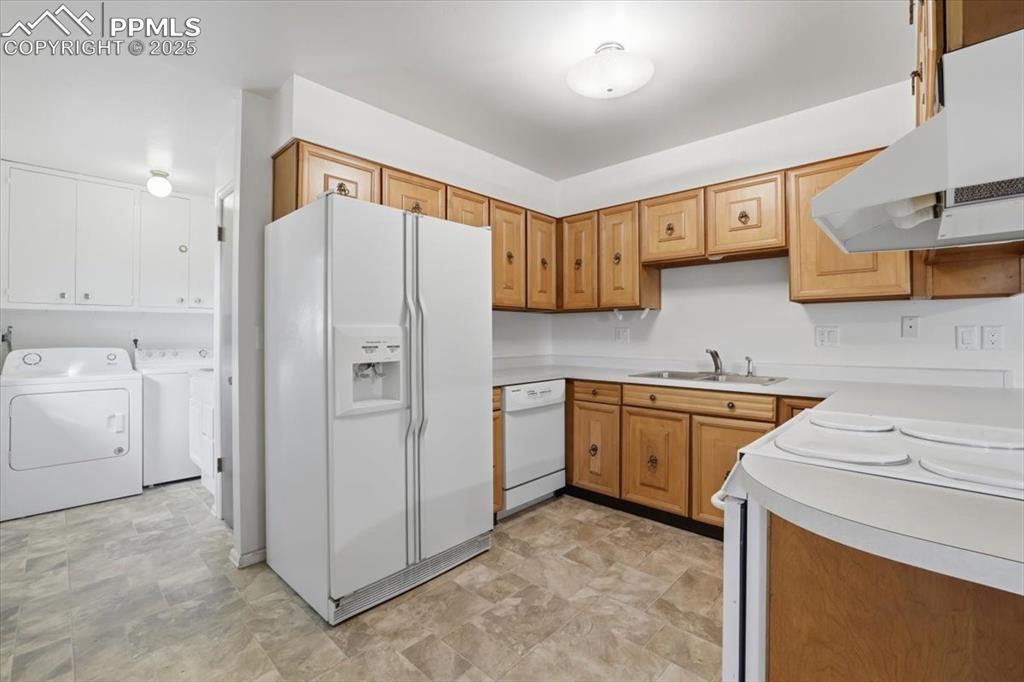 Image 33 of 50: Kitchen featuring white appliances, light countertops, washing machine and 