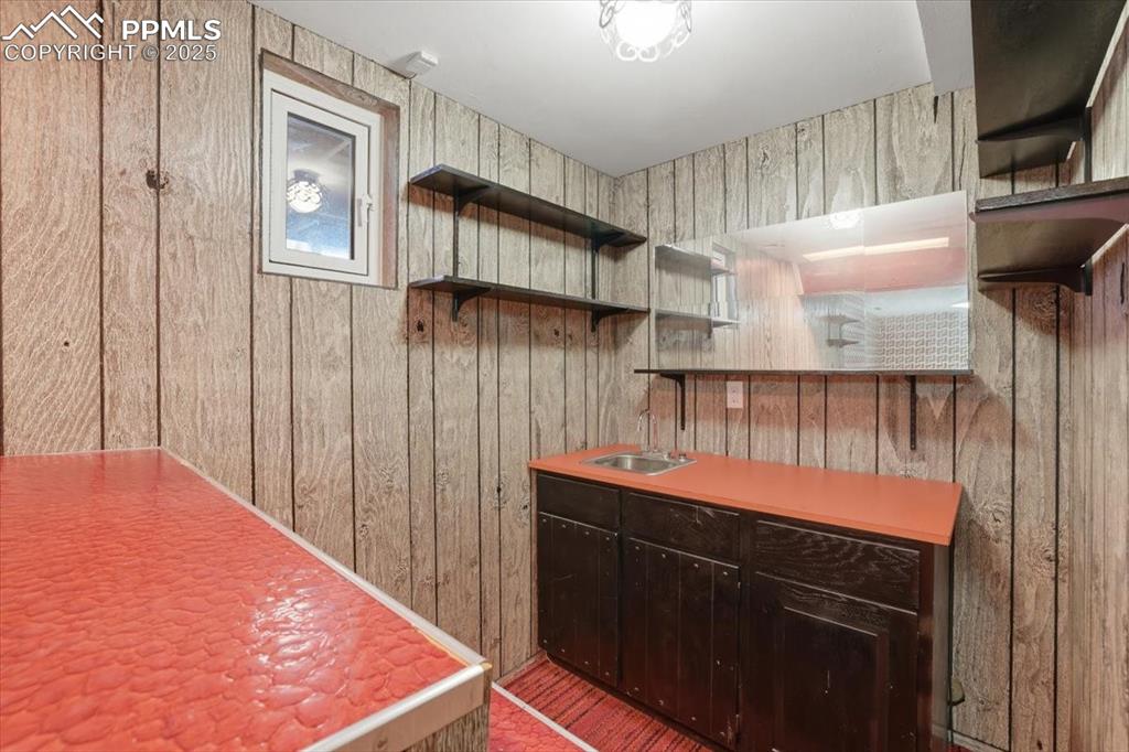 Image 41 of 50: Kitchen with open shelves, dark brown cabinets, wood walls, and light count