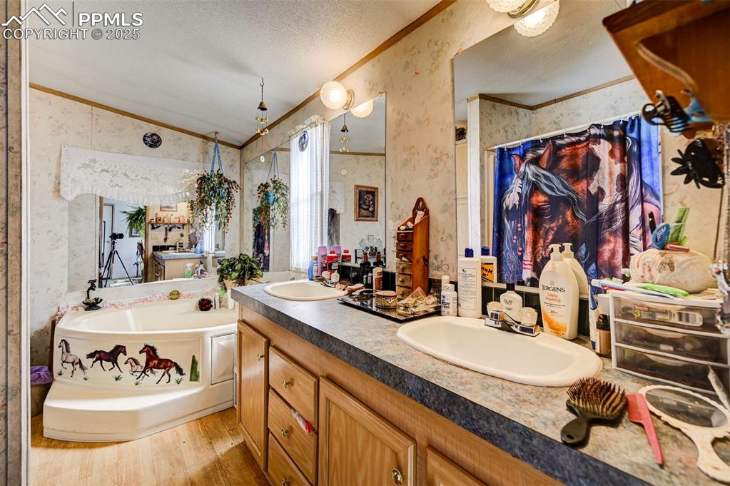Image 14 of 44: Full bathroom with crown molding, double vanity, wallpapered walls, a garde