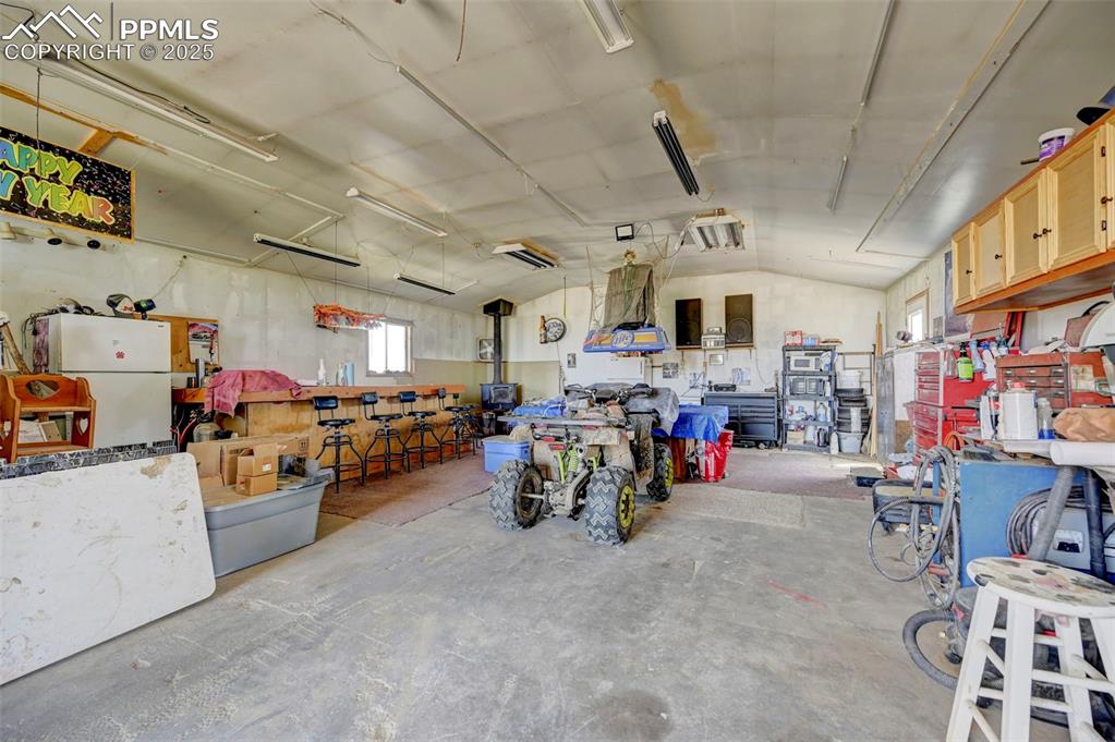 Image 21 of 44: Garage with freestanding refrigerator and a workshop area
