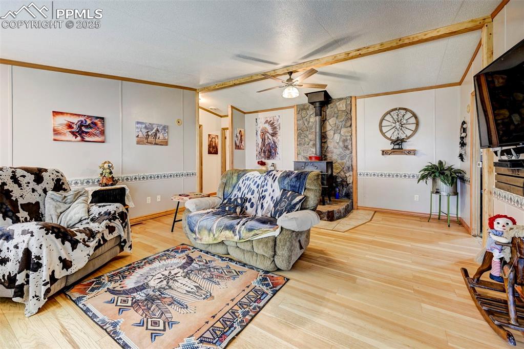 Image 6 of 44: Living area with a wood stove, lofted ceiling, a ceiling fan, ornamental mo