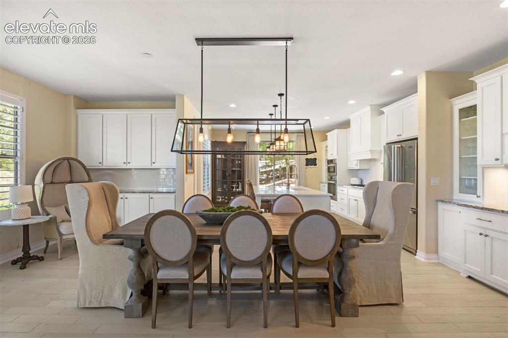 Image 10 of 49: Open-concept dining area featuring light-toned flooring, a linear chandelie