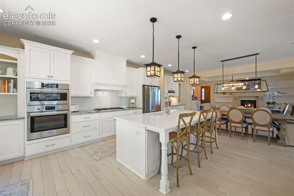 Image 13 of 49: Kitchen featuring white shaker cabinetry, stainless steel double ovens, a b