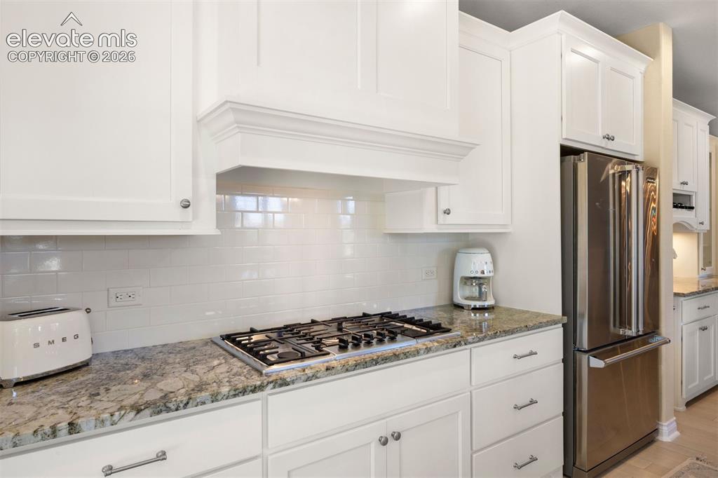 Image 16 of 49: Kitchen featuring white cabinetry, granite countertops, a gas cooktop, a su