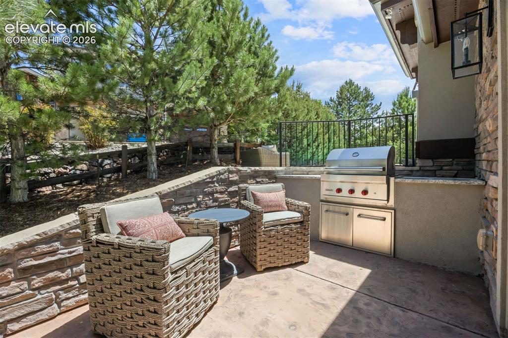 Image 18 of 49: Outdoor patio featuring a built-in stainless steel grill, stone veneer reta