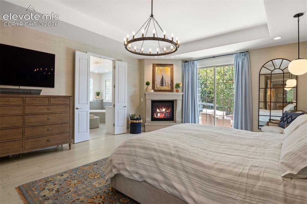 Image 21 of 49: Recessed ceiling with a contemporary chandelier, corner fireplace with a st