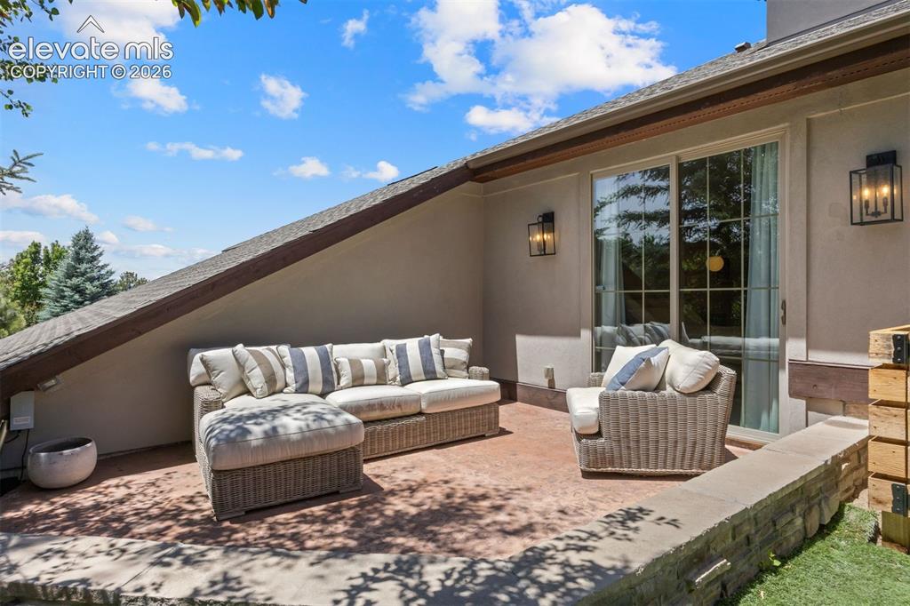 Image 22 of 49: Patio area featuring a stucco exterior, exposed timber beam, and sliding gl