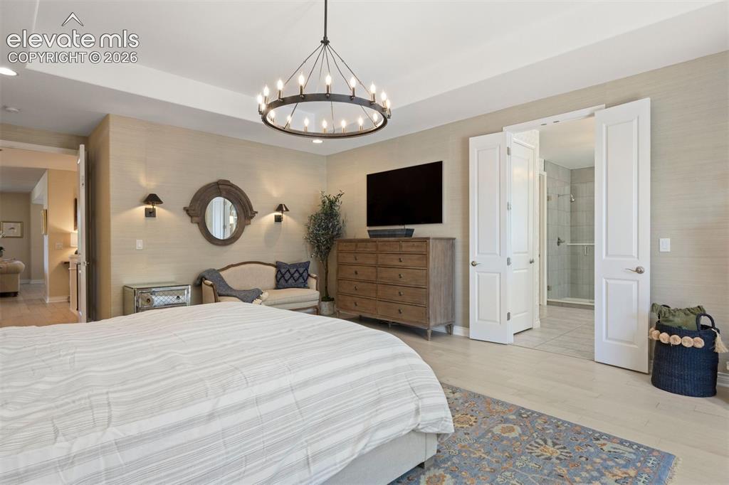 Image 24 of 49: Tray ceiling with recessed lighting and a contemporary chandelier