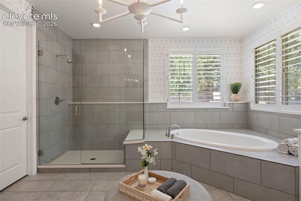 Image 27 of 49: Bathroom featuring an oval drop-in soaking tub and a glass-enclosed shower 