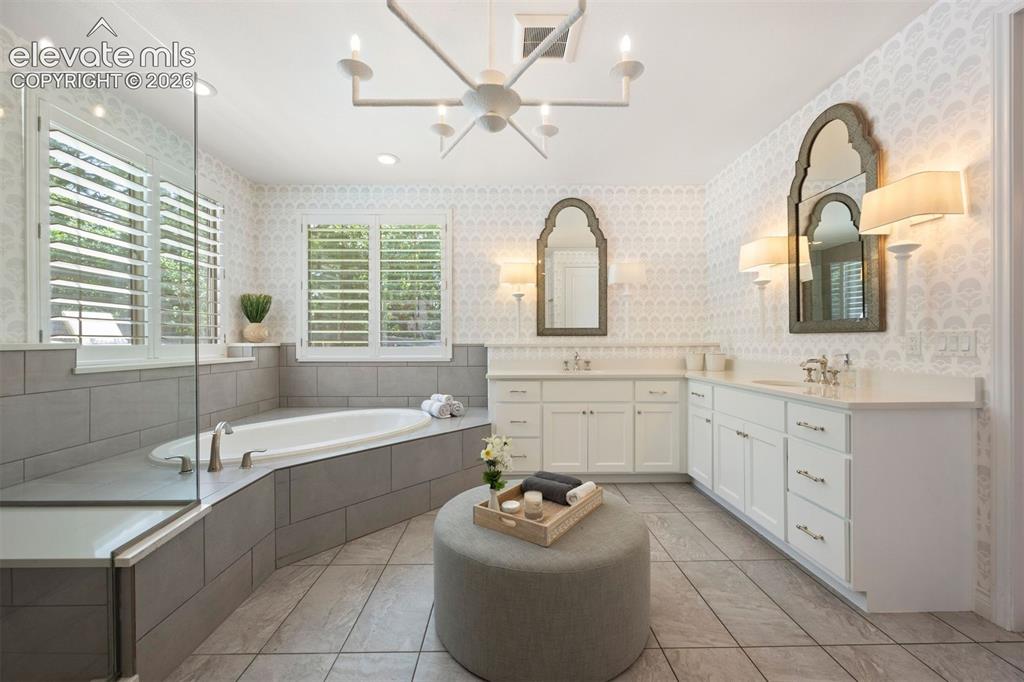 Image 28 of 49: Spacious bathroom featuring a built-in soaking tub, a separate glass-enclos
