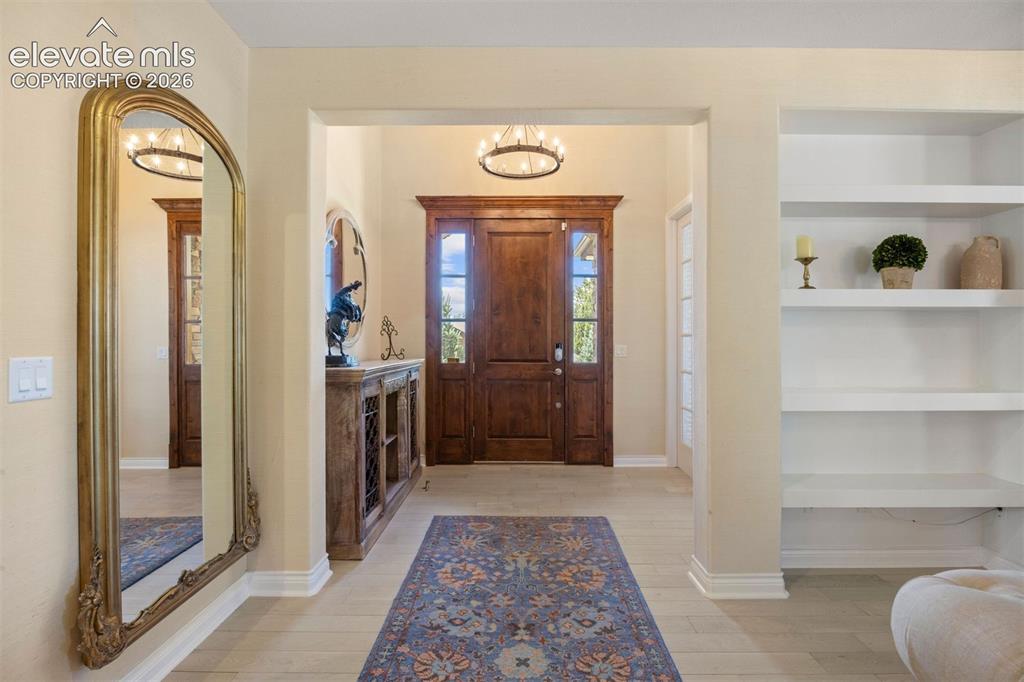 Image 3 of 49: Inviting entryway featuring a rich wood-finish door with sidelights, neutra