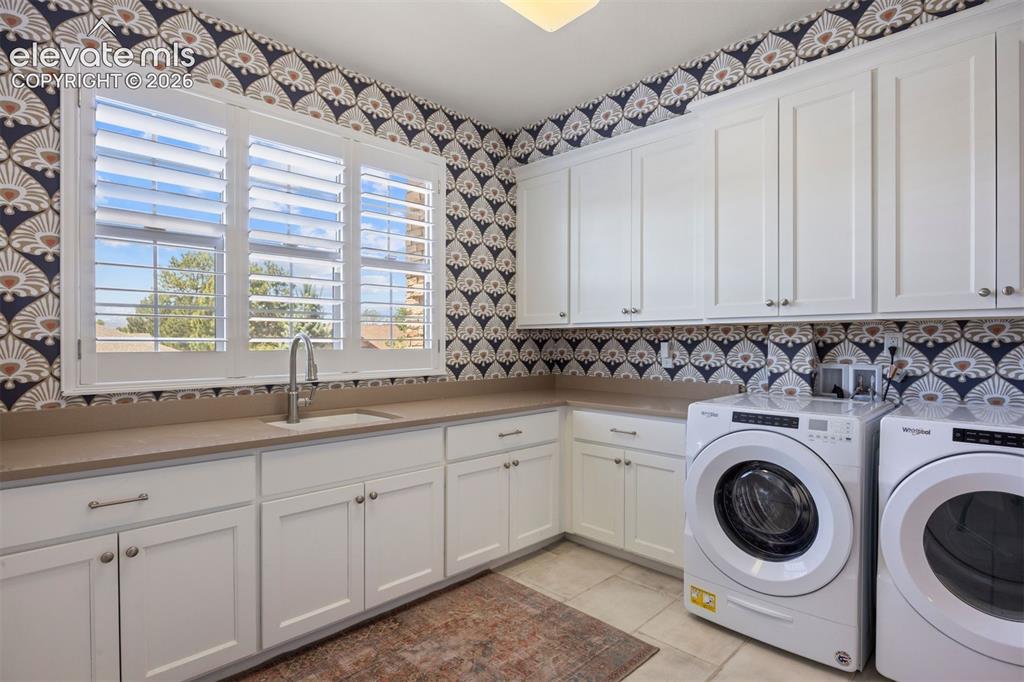 Image 32 of 49: Utility room featuring extensive white cabinetry, a built-in sink with a go