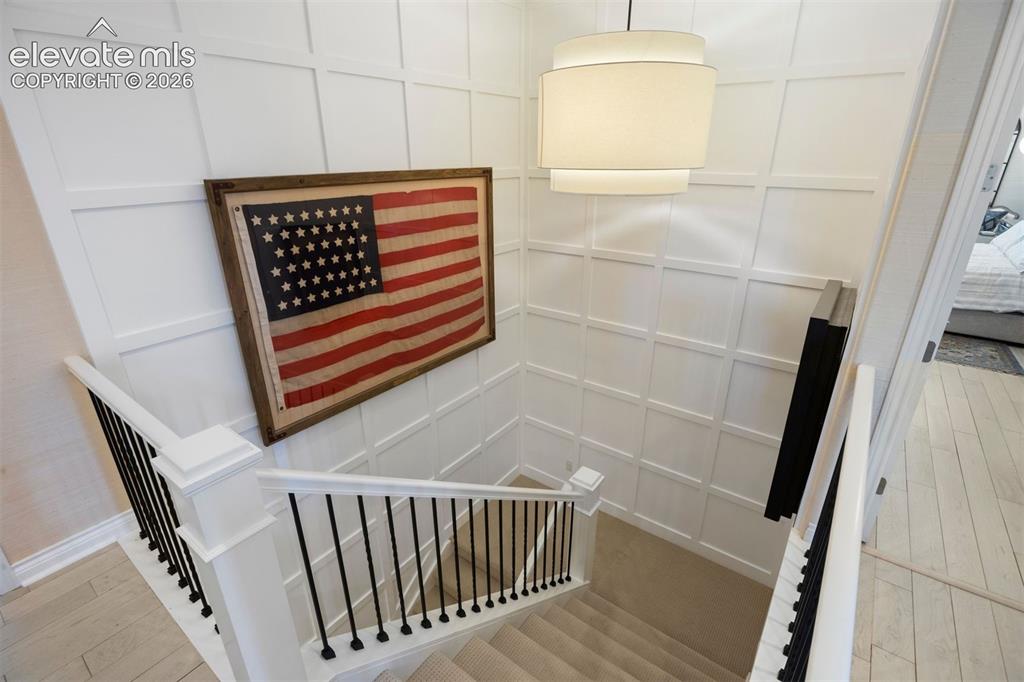 Image 34 of 49: Stairwell featuring white wainscoting, a contemporary drum pendant light, a