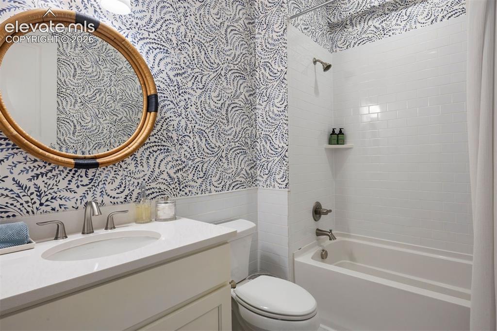 Image 37 of 49: Bathroom featuring patterned wallpaper, a white vanity with an integrated s