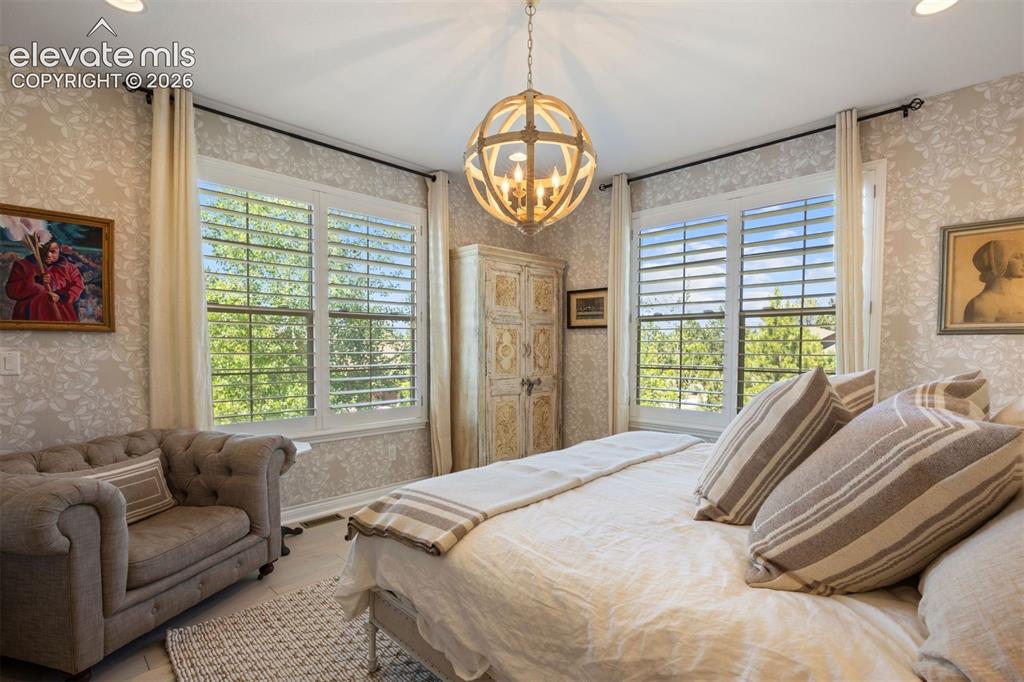 Image 4 of 49: Spacious room featuring multiple windows with plantation shutters, a wood-f