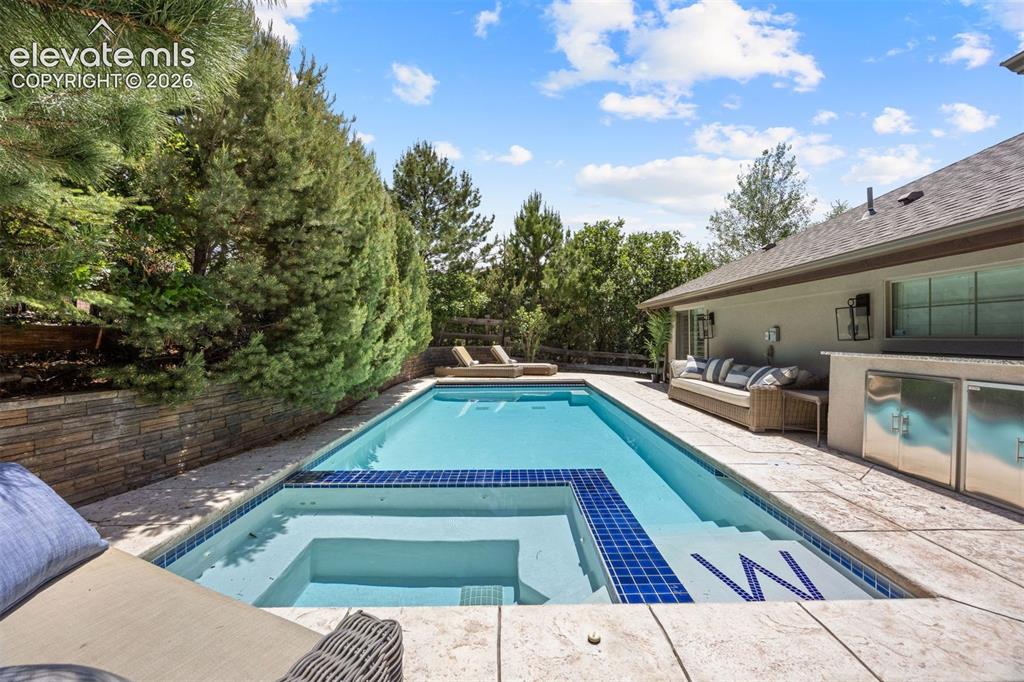 Image 42 of 49: Outdoor swimming pool featuring a built-in spa with blue tile accents