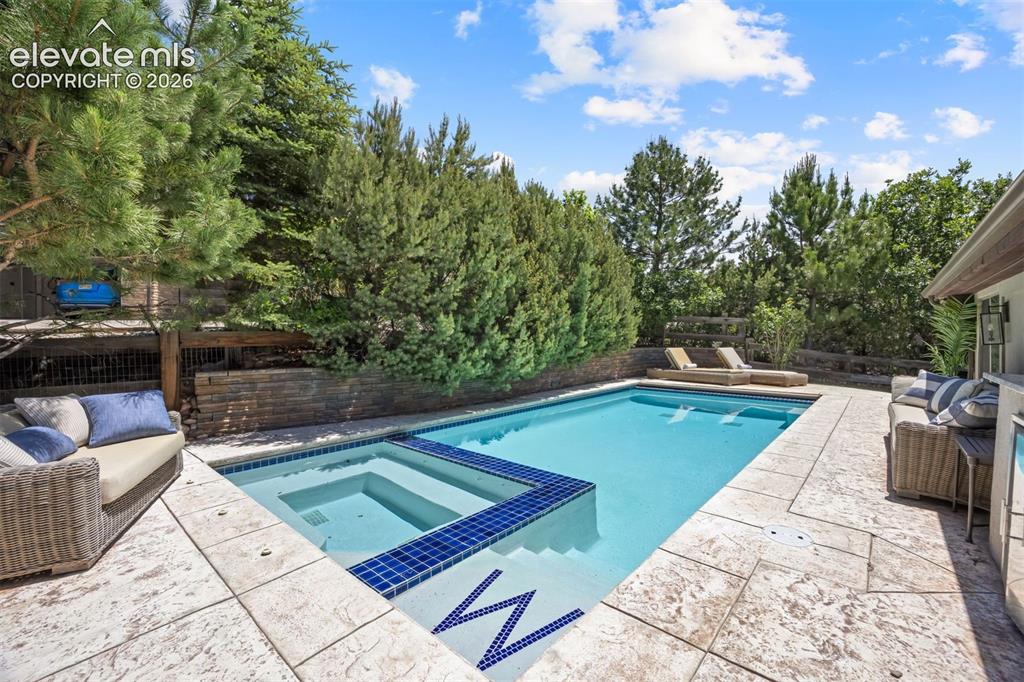 Image 43 of 49: Outdoor swimming pool featuring a built-in spa with blue mosaic tiling and 