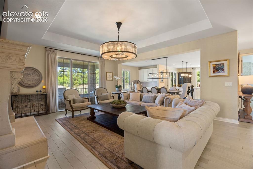 Image 7 of 49: Spacious living area featuring light wood-finish flooring and a tray ceilin