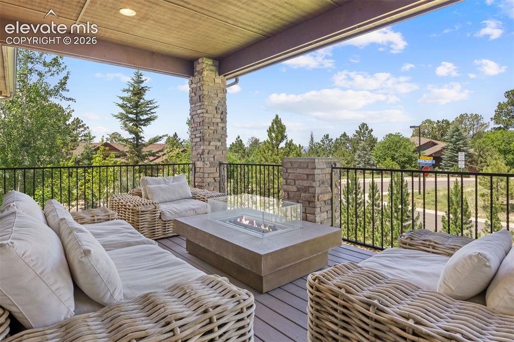 Image 8 of 49: Covered outdoor deck featuring stone-clad pillars and a built-in fire pit