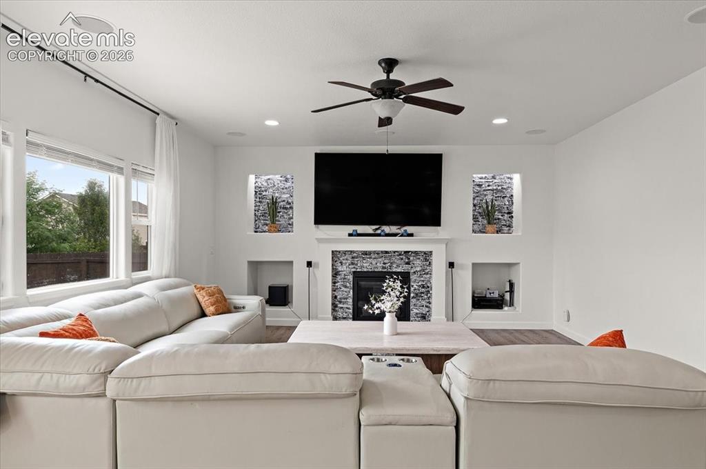Image 10 of 39: Living area featuring a fireplace with stone surround, built-in shelving, w