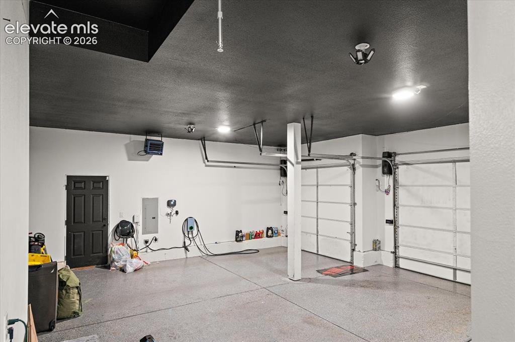 Image 26 of 39: Garage featuring dual overhead doors, a textured ceiling, durable floor coa