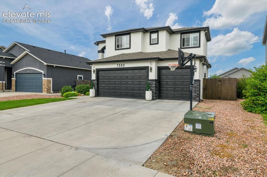 Image 31 of 39: Two-story exterior with a two-car garage, white stucco, and dark trim