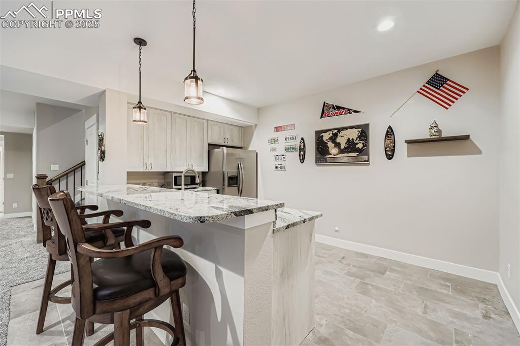 Image 26 of 42: Basement wet bar featuring dishwasher and bar seating, creating a perfect s