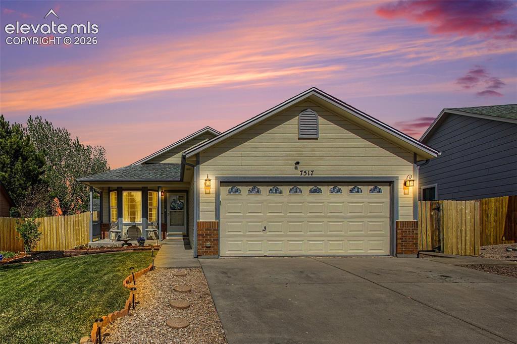Caption: Ranch-style residence featuring a two-car garage, partial brick facade, and a covered front porch
