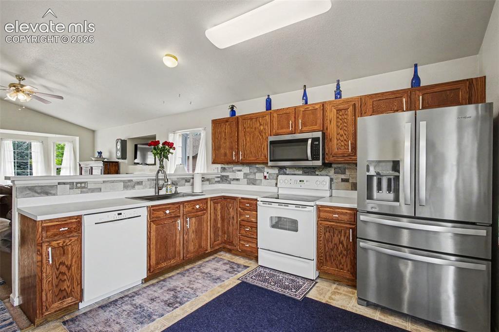 Image 10 of 33: Kitchen featuring wood cabinetry, white countertops, a mosaic tile backspla