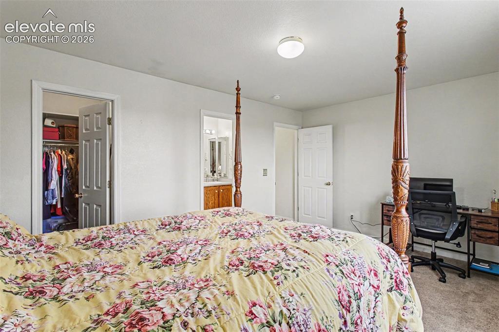Image 13 of 33: Spacious bedroom featuring light neutral walls and a ceiling-mounted light 