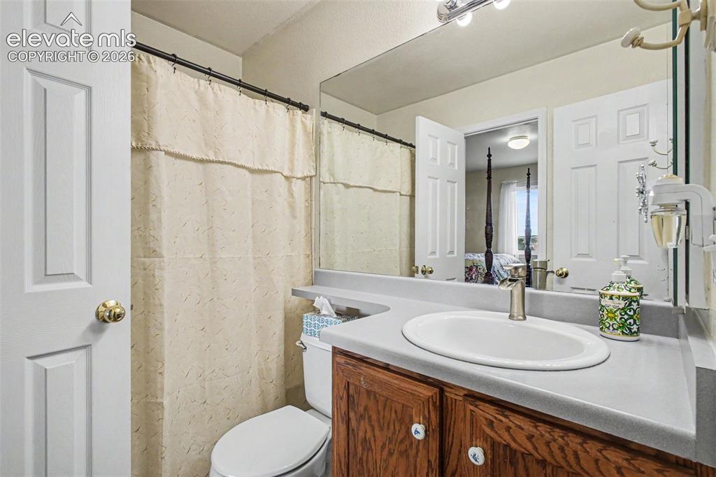 Image 16 of 33: Bathroom featuring a single vanity with wood cabinetry, a white oval sink, 