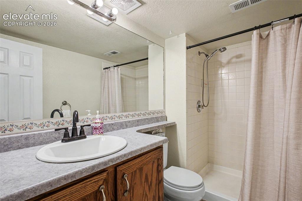 Image 17 of 33: Bathroom featuring a shower with white tile surround, a built-in vanity wit