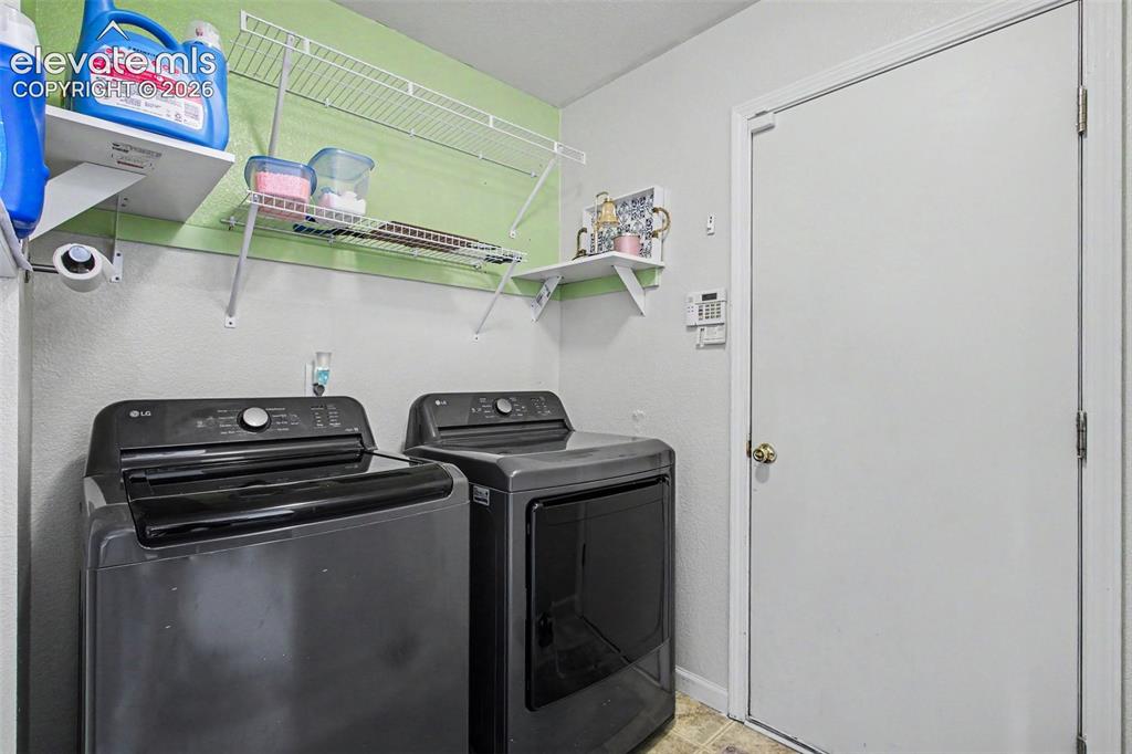 Image 18 of 33: Dedicated laundry area featuring a light green accent wall, white shelving,