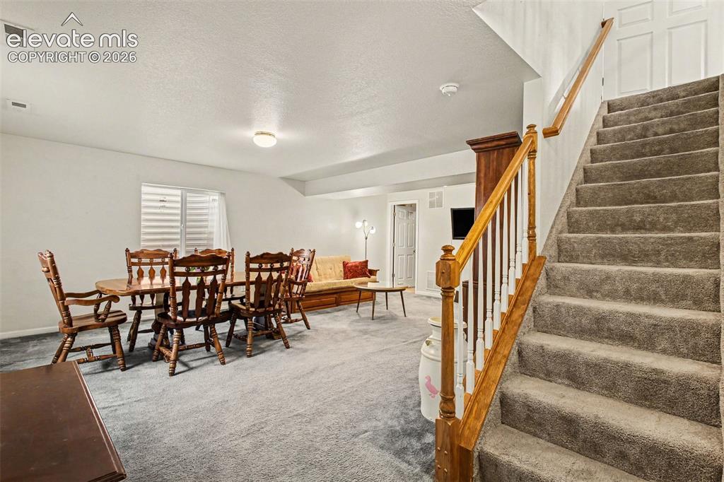 Image 20 of 33: Carpeted staircase with wood handrail and white spindles