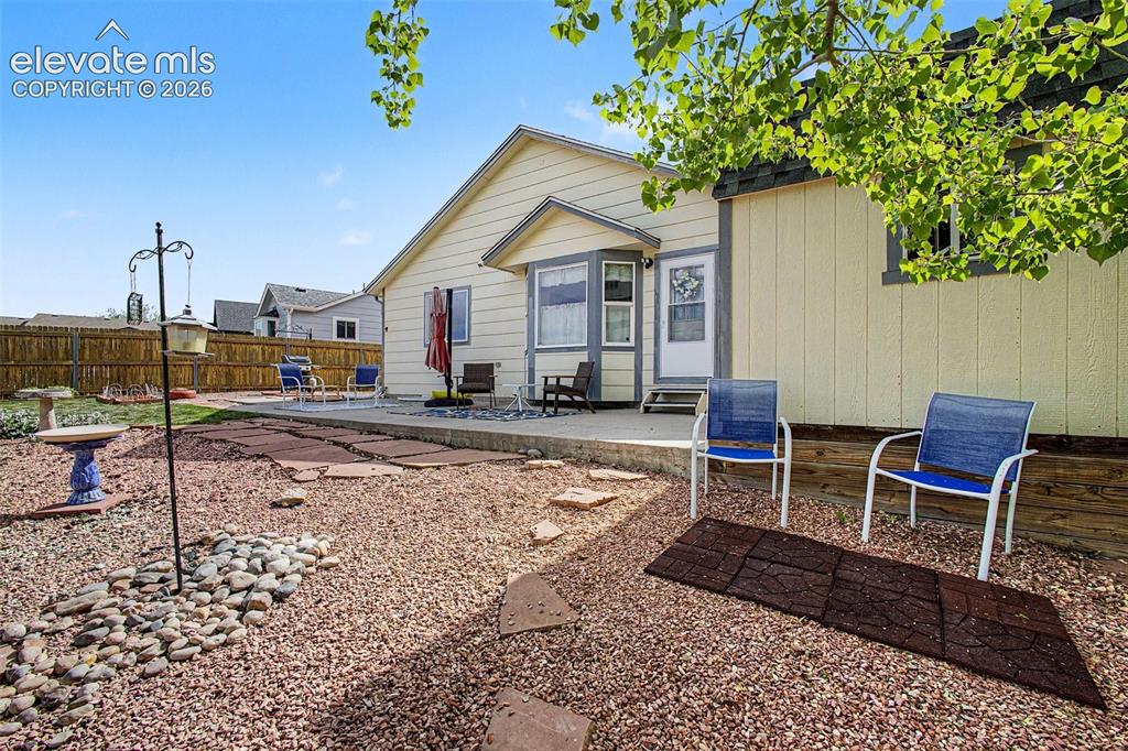 Image 23 of 33: Expansive backyard featuring a rock landscape, flagstone path, concrete pat
