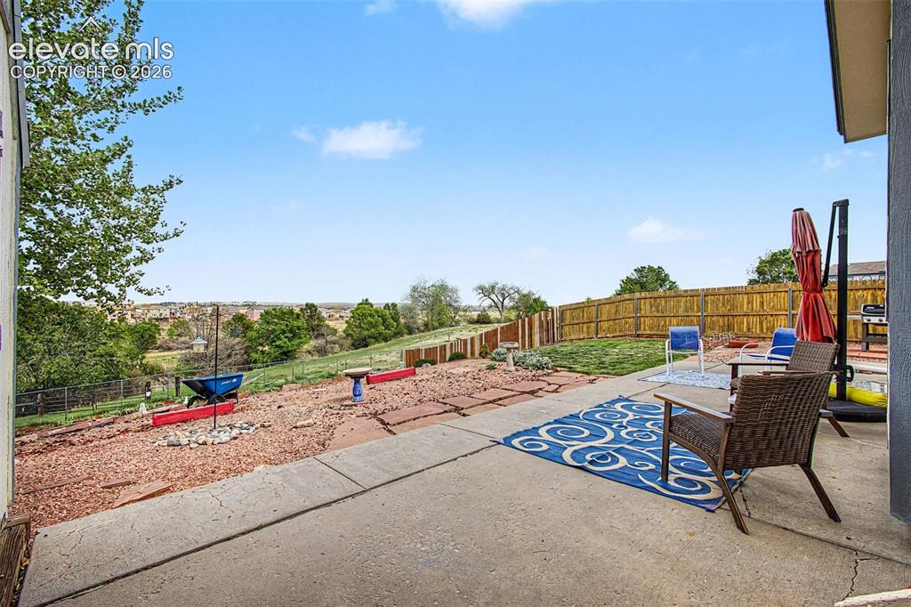 Image 24 of 33: Concrete patio area featuring an expansive terraced backyard, a wooden priv