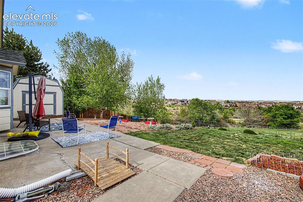 Image 25 of 33: Expansive concrete patio with a detached storage shed