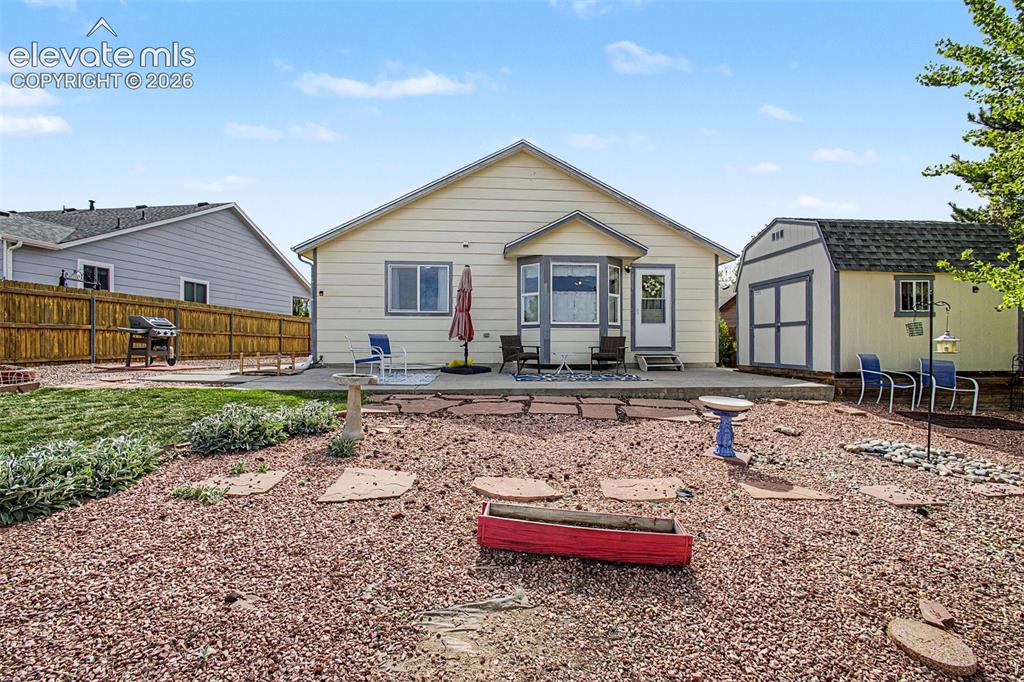 Image 26 of 33: Backyard featuring a concrete patio, bay window, and a storage shed with do