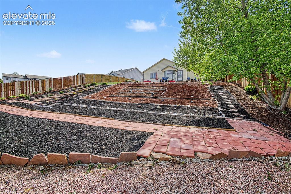 Image 29 of 33: Terraced backyard featuring brick pathways and a multi-level landscape desi