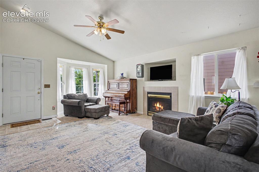 Image 3 of 33: Spacious living area featuring a vaulted ceiling with a ceiling fan, bay wi