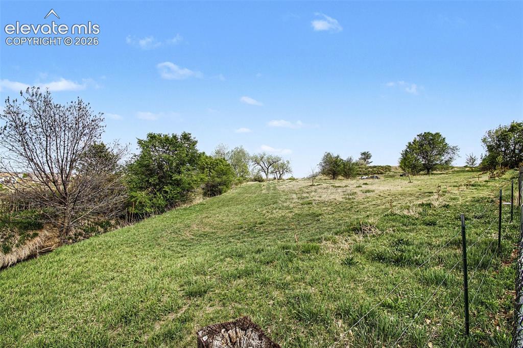 Image 30 of 33: Expansive hillside property featuring established trees and a partially fen