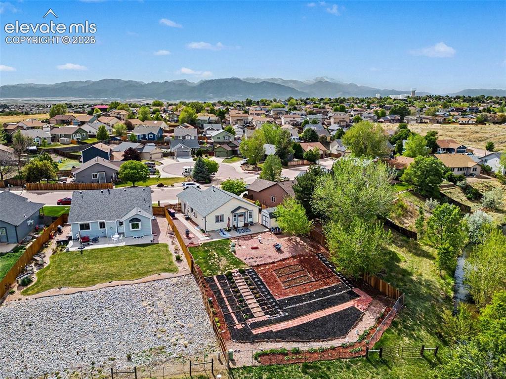 Image 33 of 33: Expansive backyard featuring a large garden area with defined beds, mature 